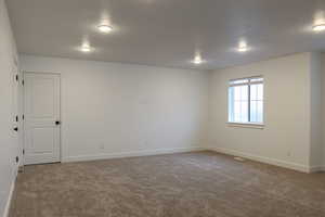 Empty room with carpet floors and a textured ceiling