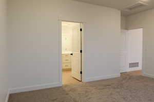 Empty room featuring light carpet and attic access
