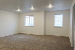 Unfurnished room with dark colored carpet and plenty of natural light