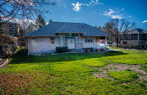 Rear view of property featuring a lawn, brick siding, and a shingled roof