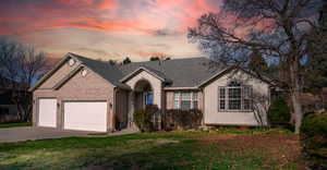 View of front facade featuring concrete driveway, a garage, a front yard, brick siding, and stucco siding