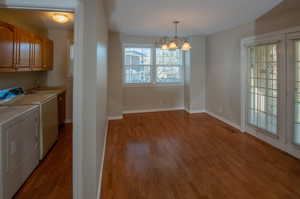 Laundry area with a chandelier, light wood-type flooring, cabinet space, and independent washer and dryer