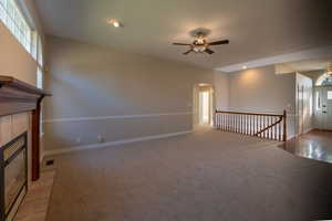 Unfurnished living room featuring healthy amount of natural light, a tile fireplace, arched walkways, light colored carpet, and recessed lighting