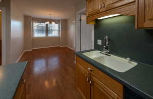Kitchen featuring brown cabinetry, a chandelier, dark wood-type flooring, and hanging light fixtures