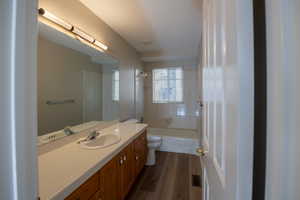 Bathroom featuring vanity, washtub / shower combination, and dark wood-type flooring