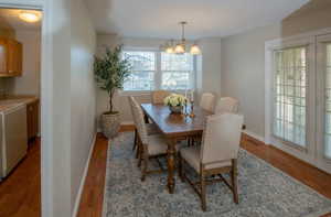 Dining space with washer / clothes dryer, light wood-style flooring, and a chandelier