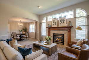 Carpeted living room featuring arched walkways, a fireplace, and a chandelier