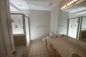 Bathroom featuring double vanity, a stall shower, and light tile patterned flooring