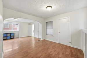 Spare room featuring a textured ceiling, wood finished floors, and arched walkways