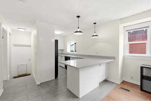 Kitchen with a peninsula, white cabinets, pendant lighting, a textured ceiling, and wood tiled floors