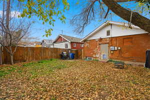 Back of property featuring a fenced backyard, an outdoor fire pit, and a gate