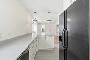Kitchen with black appliances, white cabinetry, pendant lighting, a peninsula, and arched walkways