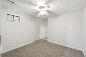 Carpeted empty room with a textured ceiling and a ceiling fan
