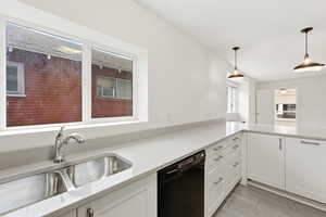 Kitchen with dishwasher, hanging light fixtures, white cabinets, light stone counters, and light wood finished floors