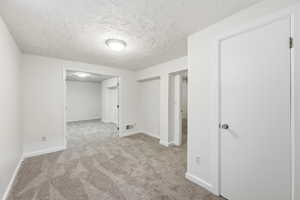Below grade area featuring a textured ceiling and light colored carpet