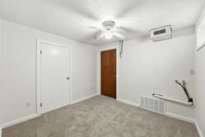 Unfurnished bedroom with a textured ceiling, carpet, and a ceiling fan