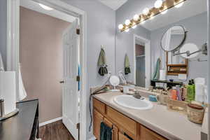 Full bath with vanity and dark wood-style flooring