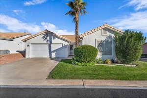 Mediterranean / spanish home with stucco siding, concrete driveway, a tile roof, an attached garage, and a front yard