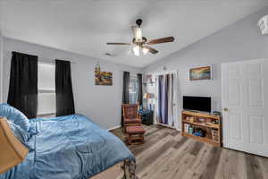 Bedroom featuring vaulted ceiling, wood finished floors, a ceiling fan, and multiple windows