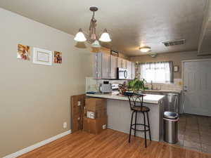 Kitchen with tile counters, decorative backsplash, a kitchen breakfast bar, and decorative light fixtures