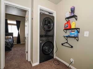Laundry room featuring dark carpet and stacked washing machine and dryer