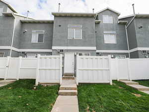 View of front of house with stucco siding, a fenced backyard, and a gate