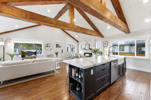 Kitchen featuring open floor plan, light stone counters, plenty of natural light, a kitchen island with sink, and recessed lighting