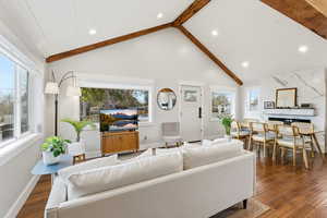 Living room with dark wood-style floors, beam ceiling, high vaulted ceiling, and recessed lighting