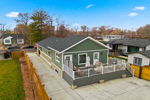 View of front of home with a wooden deck, a residential view, roof with shingles, and an outbuilding