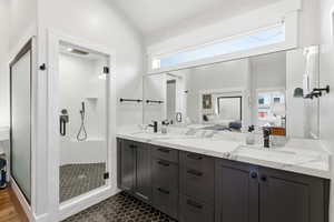Ensuite bathroom with double vanity, a shower stall, plenty of natural light, and lofted ceiling