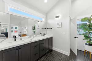 Bathroom featuring double vanity and vaulted ceiling