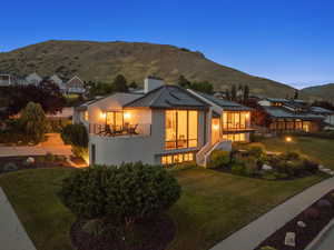 View of front of house featuring a balcony, a front yard, a chimney, and a metal roof