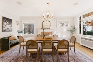 Dining space with wood finished floors, a chandelier, a fireplace, and plenty of natural light