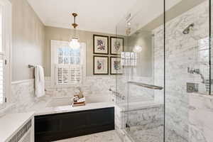 Bathroom with a bath, a marble finish shower, radiator heating unit, wainscoting, and crown molding