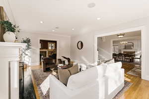 Living area with a fireplace, wood finished floors, ornamental molding, a chandelier, and stairs