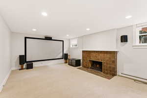 Carpeted cinema room with a tiled fireplace, baseboard heating, and recessed lighting