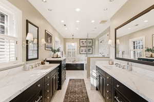 Bathroom with two vanities, a walk in shower, a bath, ornamental molding, and light marble finish floors