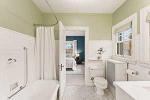 Bathroom with wainscoting, ensuite bathroom, shower / bath combo, tile walls, and vanity