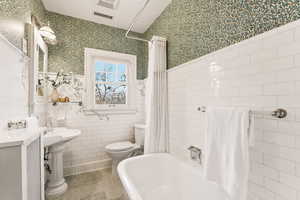 Full bath featuring wallpapered walls, tile patterned flooring, shower / bath combo, and a wainscoted wall