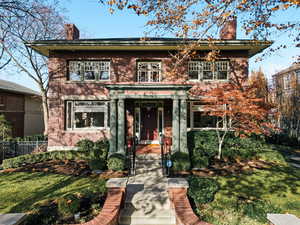 View of front of house featuring a chimney and brick siding