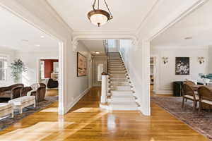 Foyer entrance featuring stairway, wood finished floors, and crown molding