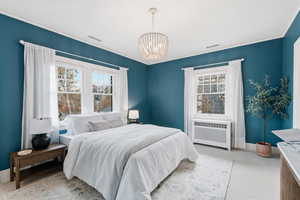 Bedroom featuring radiator heating unit, a chandelier, light carpet, and crown molding