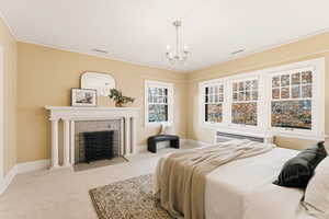 Bedroom featuring carpet floors, a fireplace, a chandelier, radiator, and crown molding
