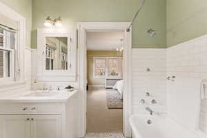 Bathroom with light carpet, vanity, radiator heating unit, washtub / shower combination, and ensuite bath