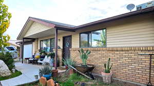 View of exterior entry with a porch, brick and vinyl siding, and an attached garage