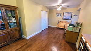 Bedroom featuring dark wood-style flooring, a closet, and a ceiling fan