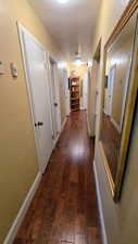 Hall featuring dark wood finished floors and baseboards