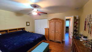 Bedroom featuring dark wood-style floors, a closet, and a ceiling fan