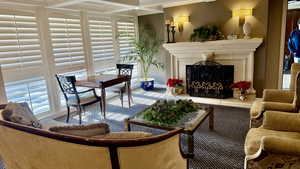 Living area featuring a fireplace with raised hearth, coffered ceiling, ornamental molding, and beam ceiling