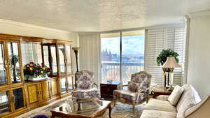 Living area with a textured ceiling, ornamental molding, healthy amount of natural light, a wall of windows, and a city view